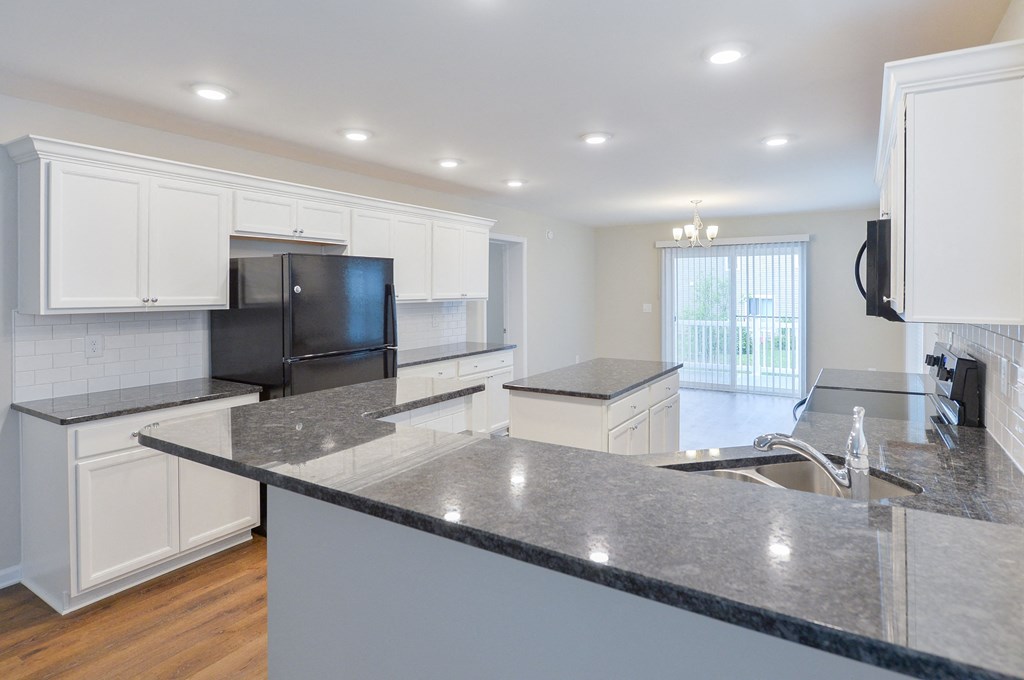 a large kitchen with white cabinets and granite counter tops