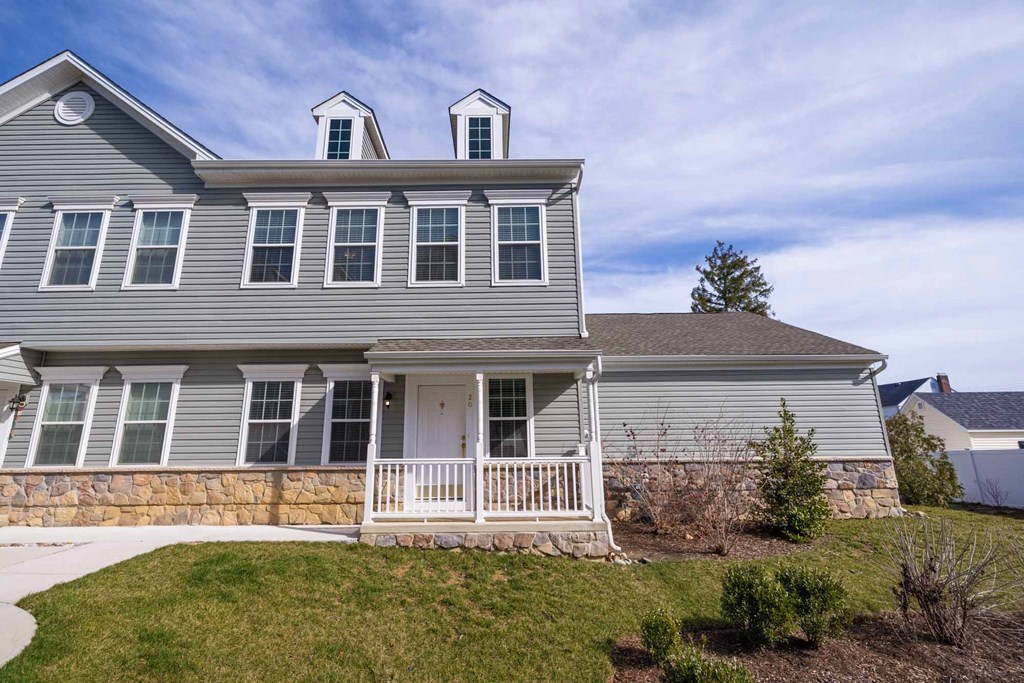 a blue house with a white front porch and a stone wall