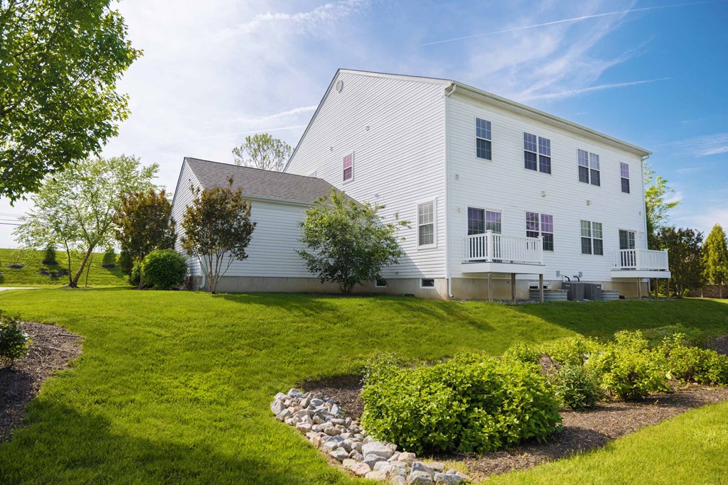 a white house on a hill with a lawn and a garden
