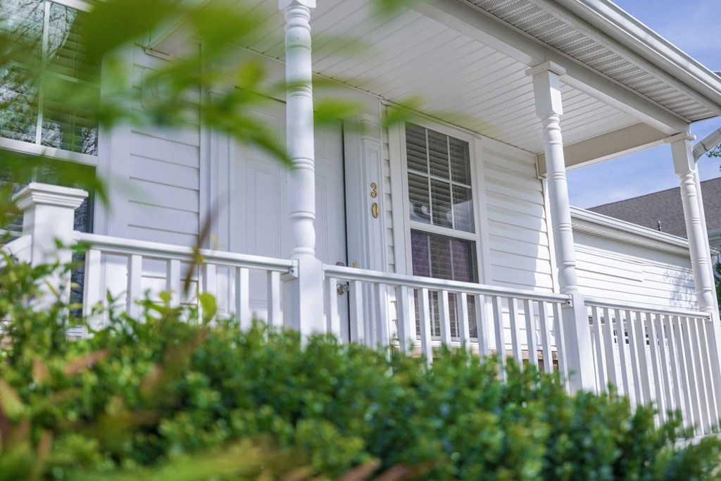 the front of a white house with a porch