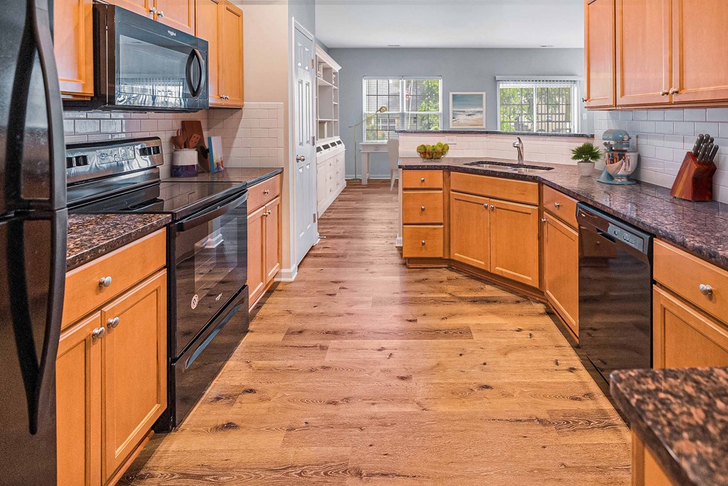 a large kitchen with wooden floors and black appliances