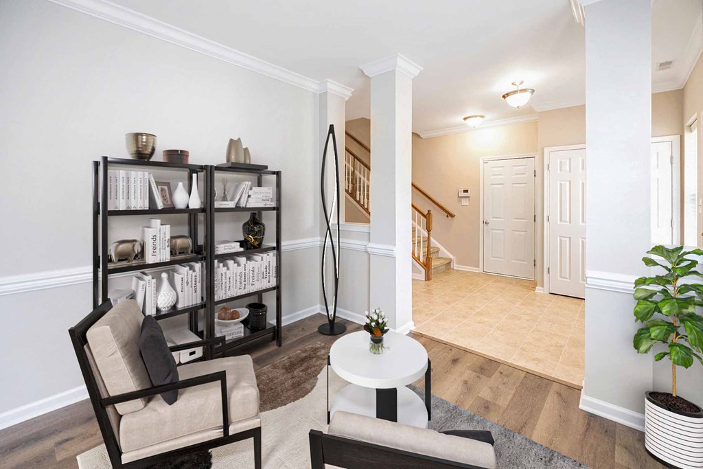 a living room with two chairs and a table and a hallway with a staircase