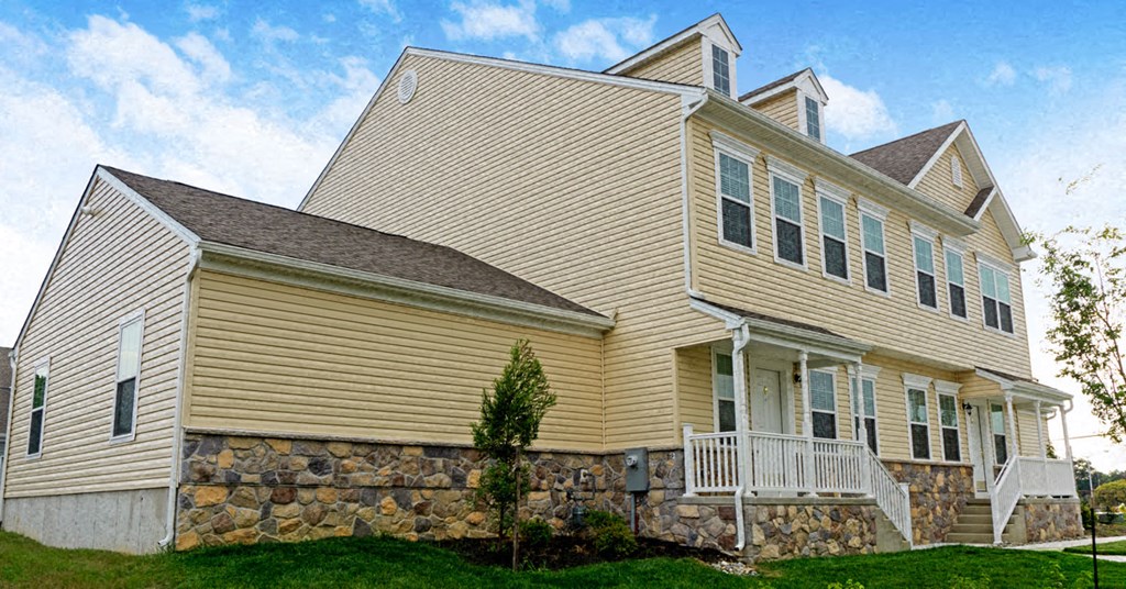 a yellow house with a stone wall in front of it