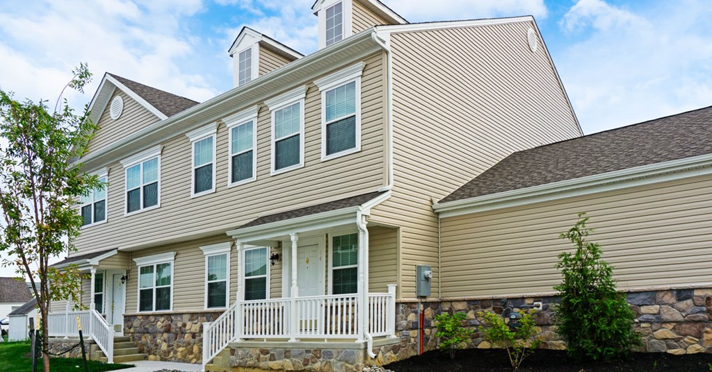 the front of a house with a stone wall
