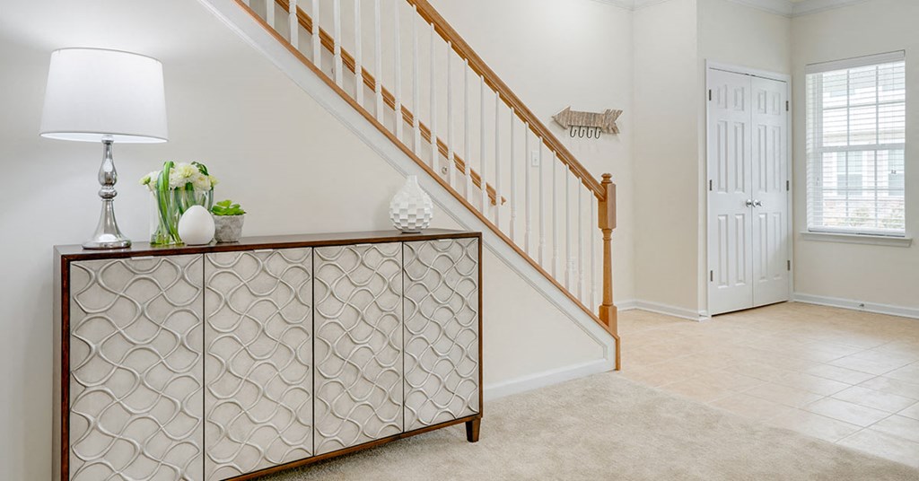 a entryway with a dresser and a staircase in a home