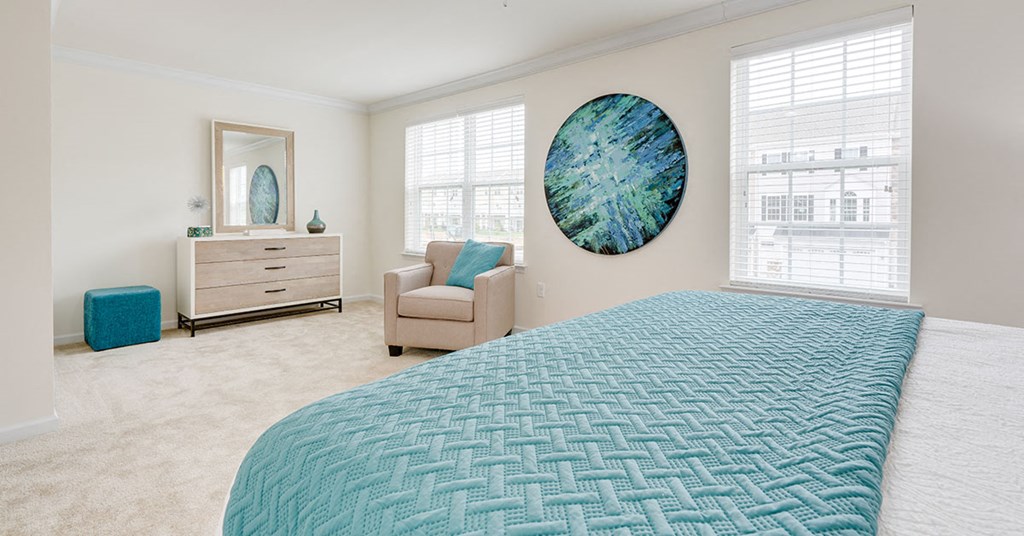 a bedroom with a bed and a chair and a painting on the wall