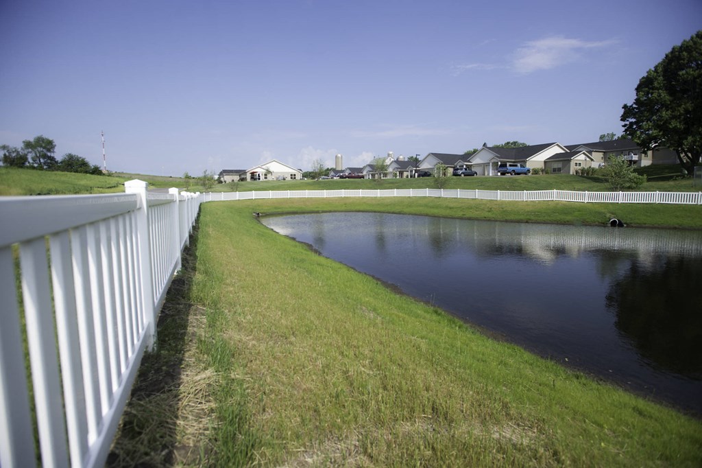 a pond in a neighborhood with a white fence