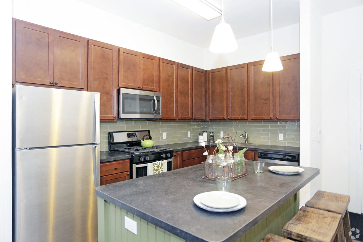 A kitchen with a stainless steel refrigerator and wooden cabinets.