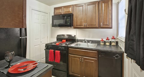 a kitchen with black appliances and wooden cabinets and a sink