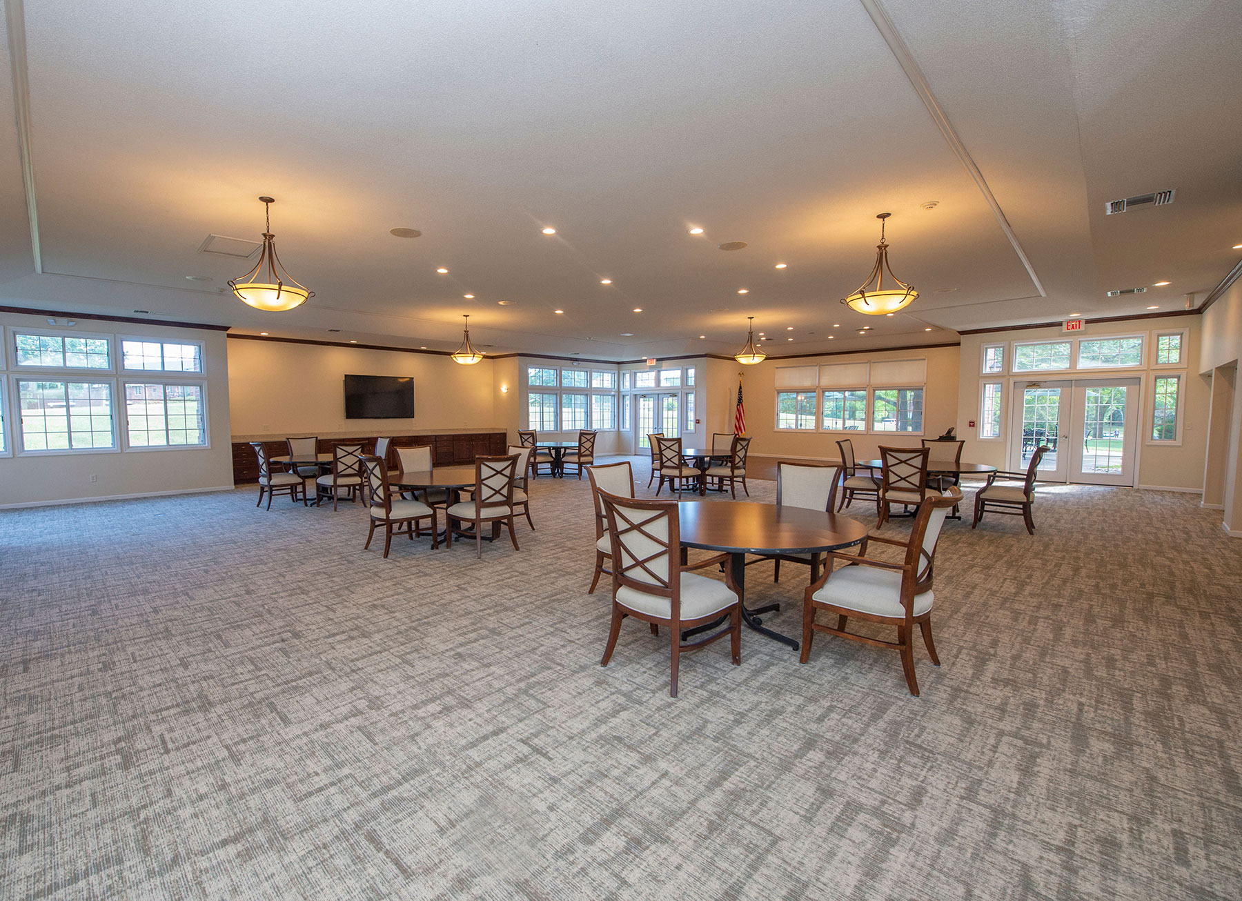 a community room with tables and chairs and a tv