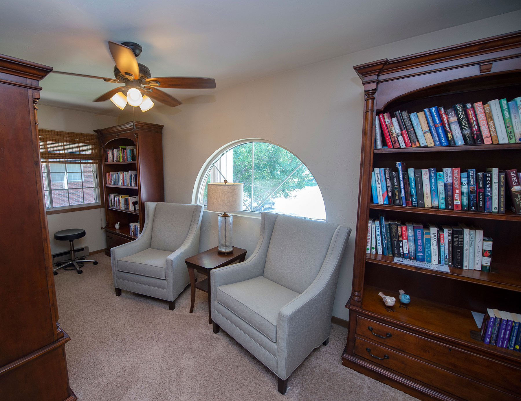 a living room with three chairs and a book shelf