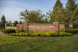 a sign for forest hills highlands with grass and flowers