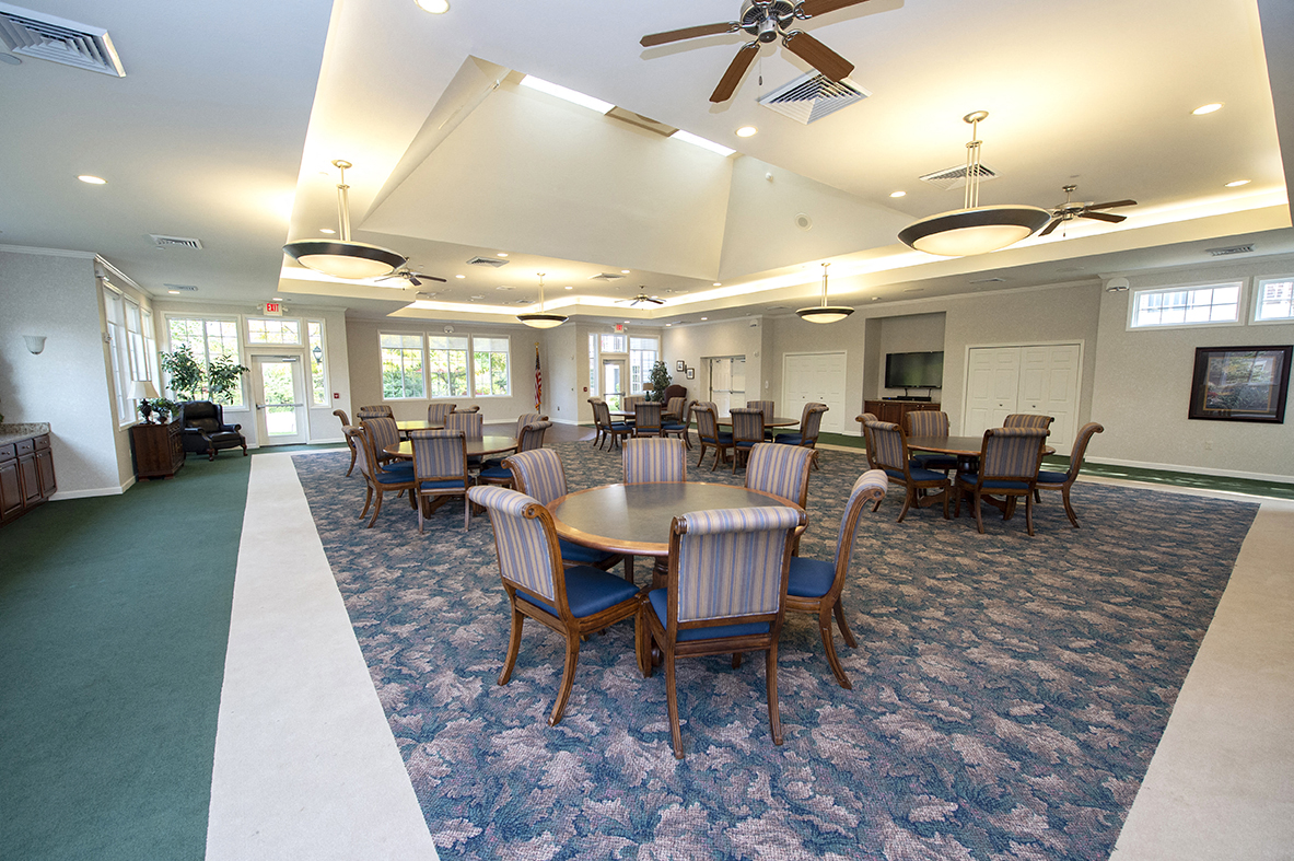 a large room with tables and chairs and a ceiling fan