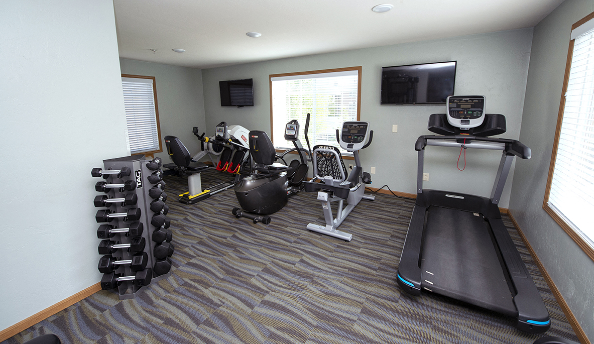 a gym with cardio equipment and a tv in the corner of a room
