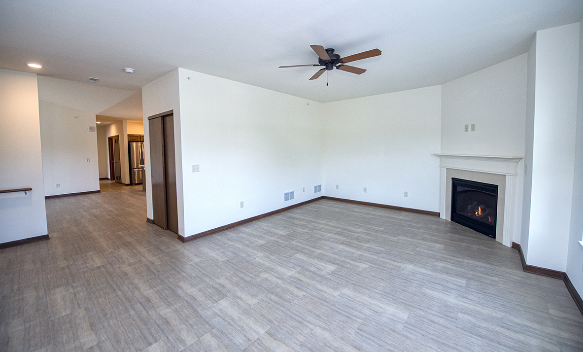 an empty living room with a fireplace and a ceiling fan