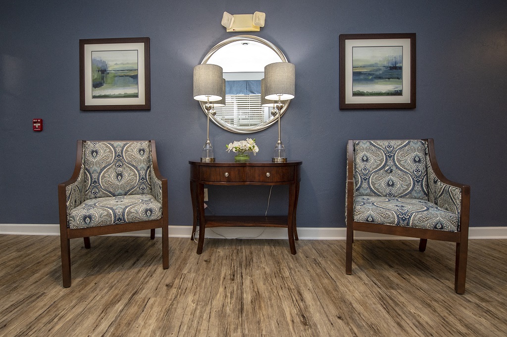 a living room with two chairs and a table and a mirror
