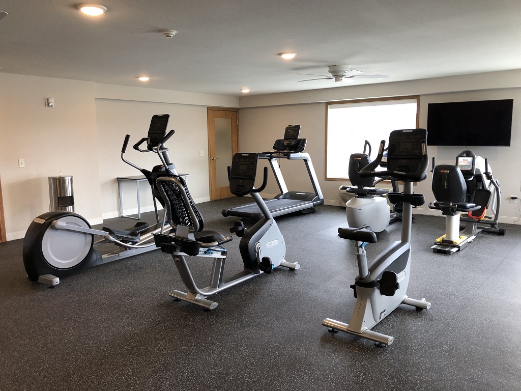 a gym with several exercise bikes and a tv