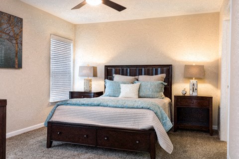 A bedroom with a bed, nightstands, and a ceiling fan.