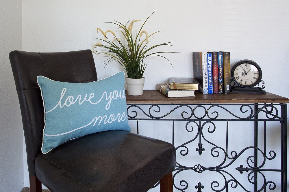 Sage Creek Apartments chair with accent pillow and table with books
