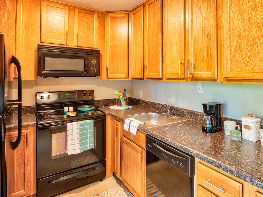 A kitchen with wooden cabinets and black appliances.