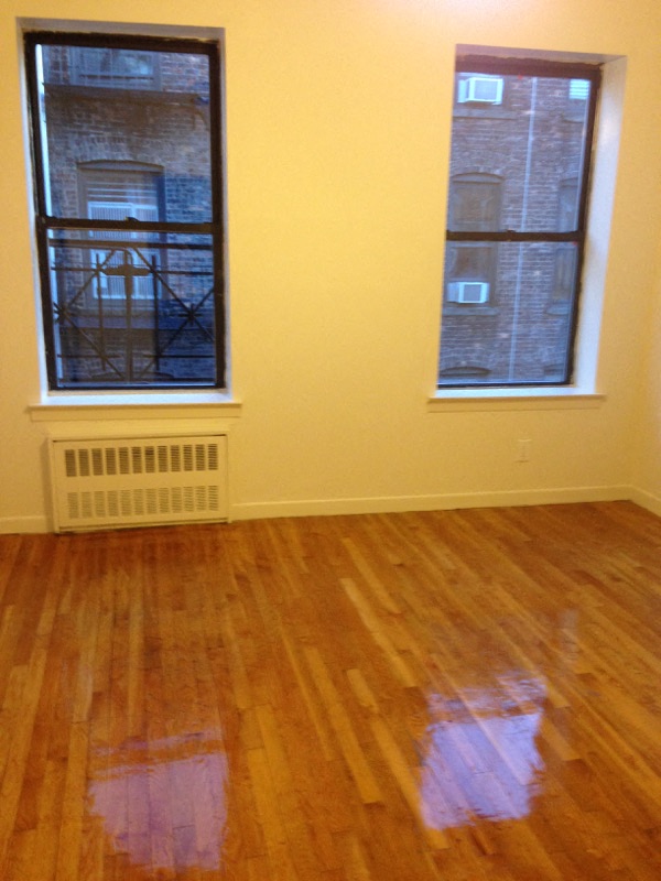an empty room with a hard wood floor and two windows