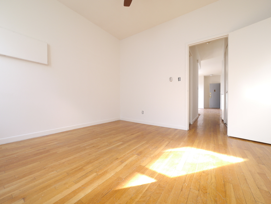 an empty living room with wood floors and white walls