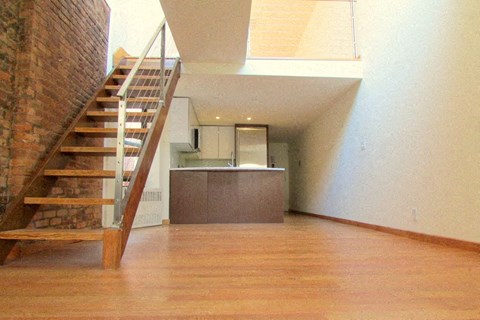 an empty living room with a staircase and a kitchen