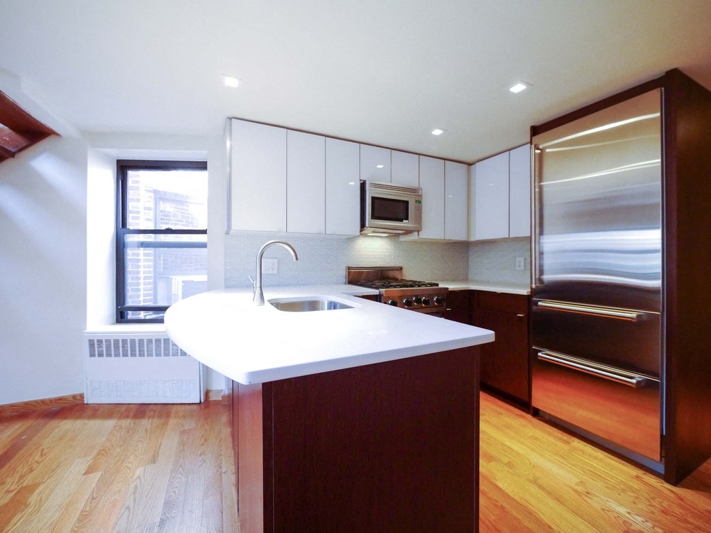a kitchen with a white counter top and a stainless steel refrigerator