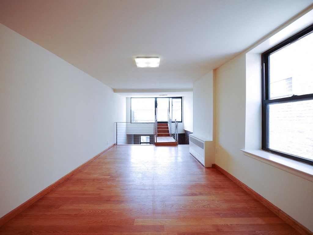 an empty living room with a wooden floor and a window