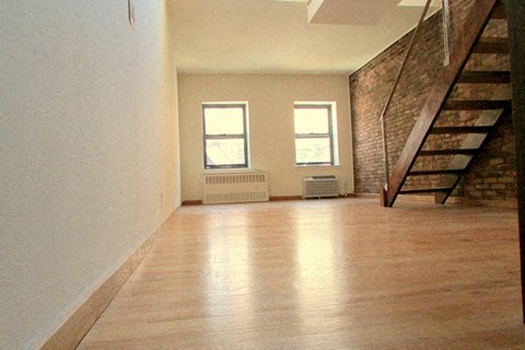an empty living room with a staircase and a wood floor