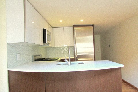 an empty kitchen with white cabinets and a sink