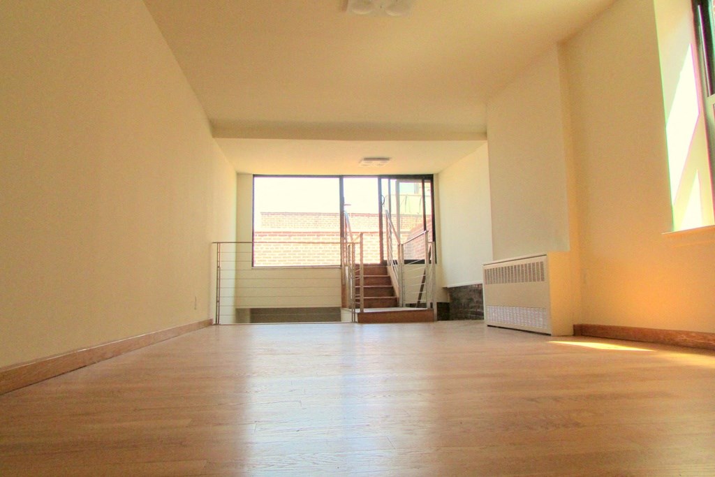 an empty living room with wood floors and a staircase