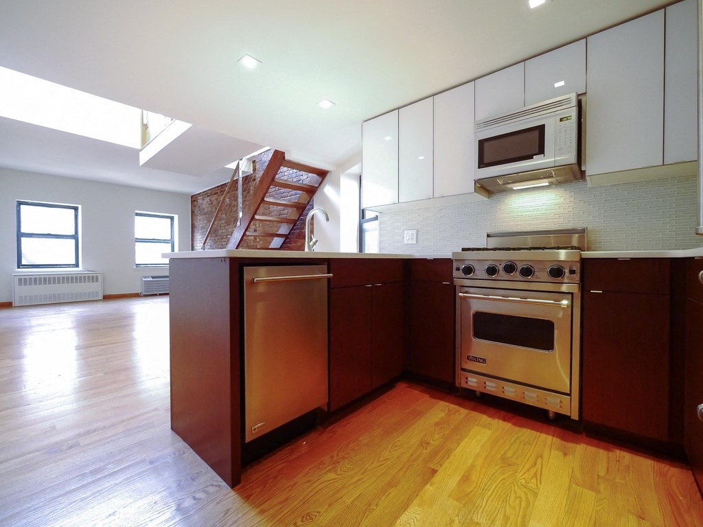 an empty kitchen with wooden floors and white cabinets