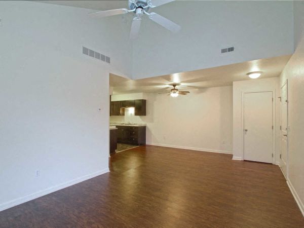 an empty living room with a ceiling fan