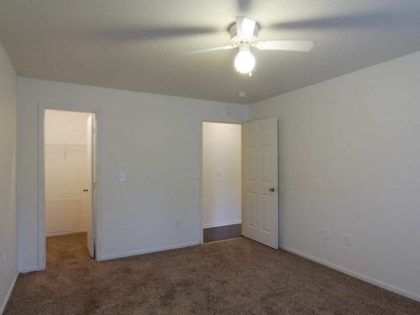 an empty living room with a ceiling fan and a door