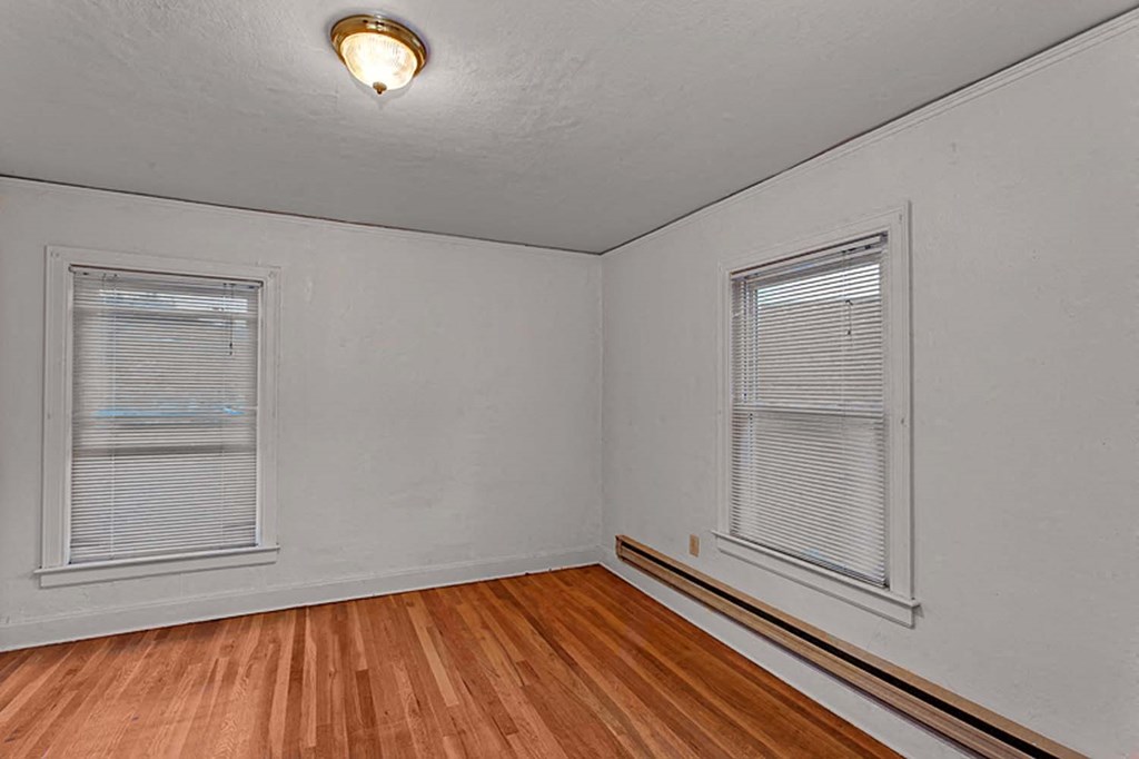 an empty room with a hard wood floor and two windows