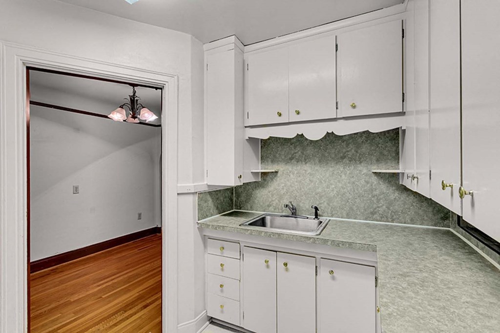 an empty kitchen with white cabinets and a sink