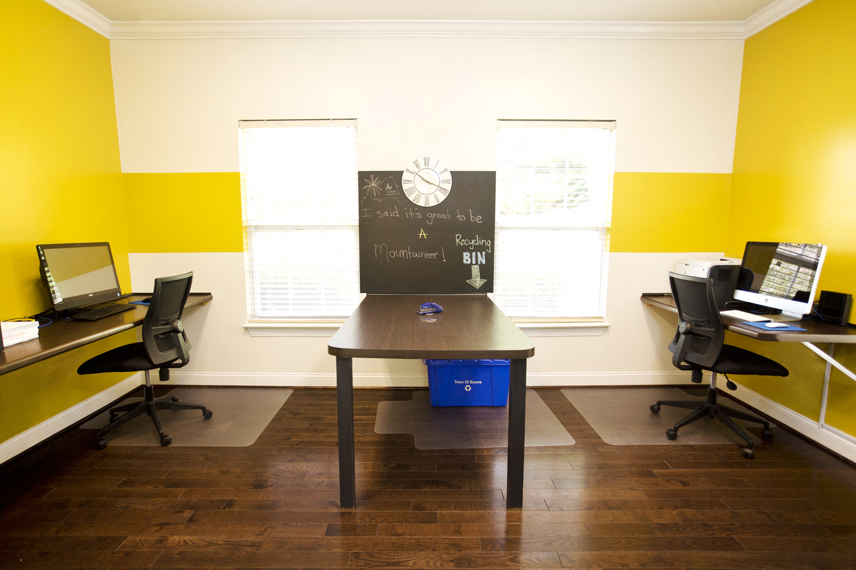an office with a desk with a chalkboard and desks with computers