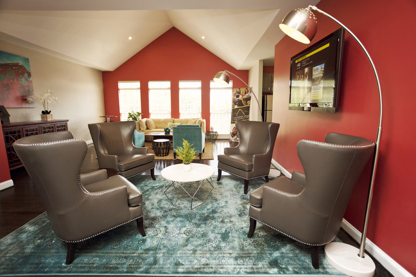 a living room with red walls and leather chairs and a rug