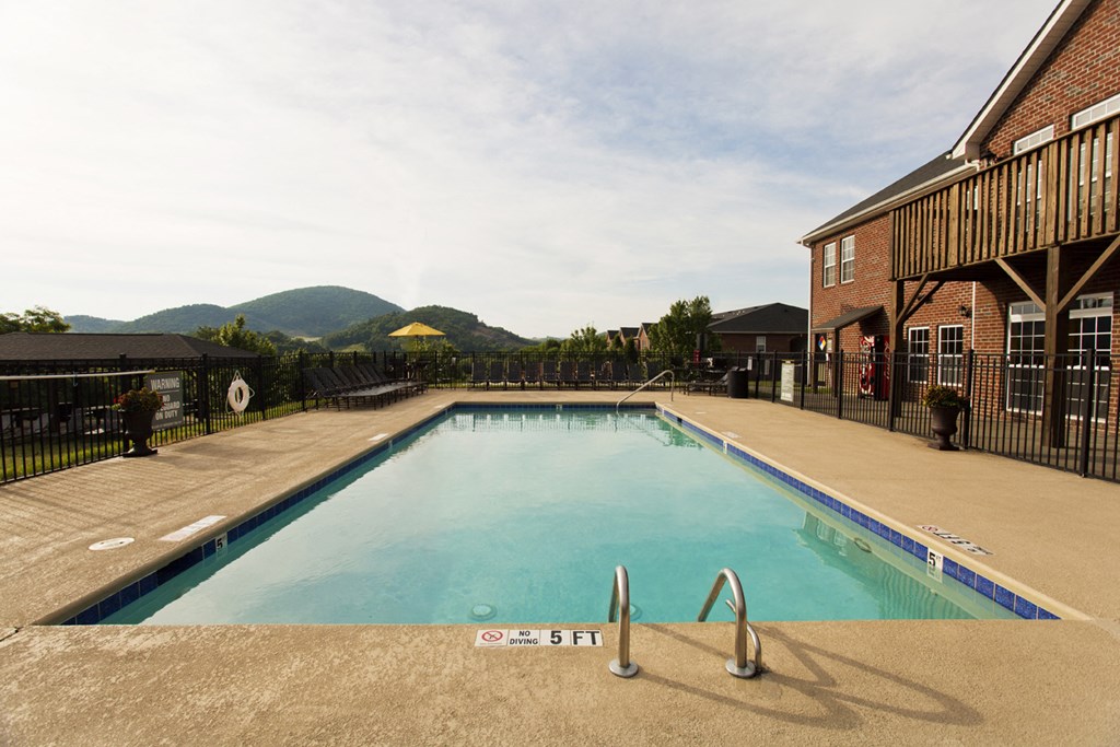 a swimming pool with a building and mountains in the background