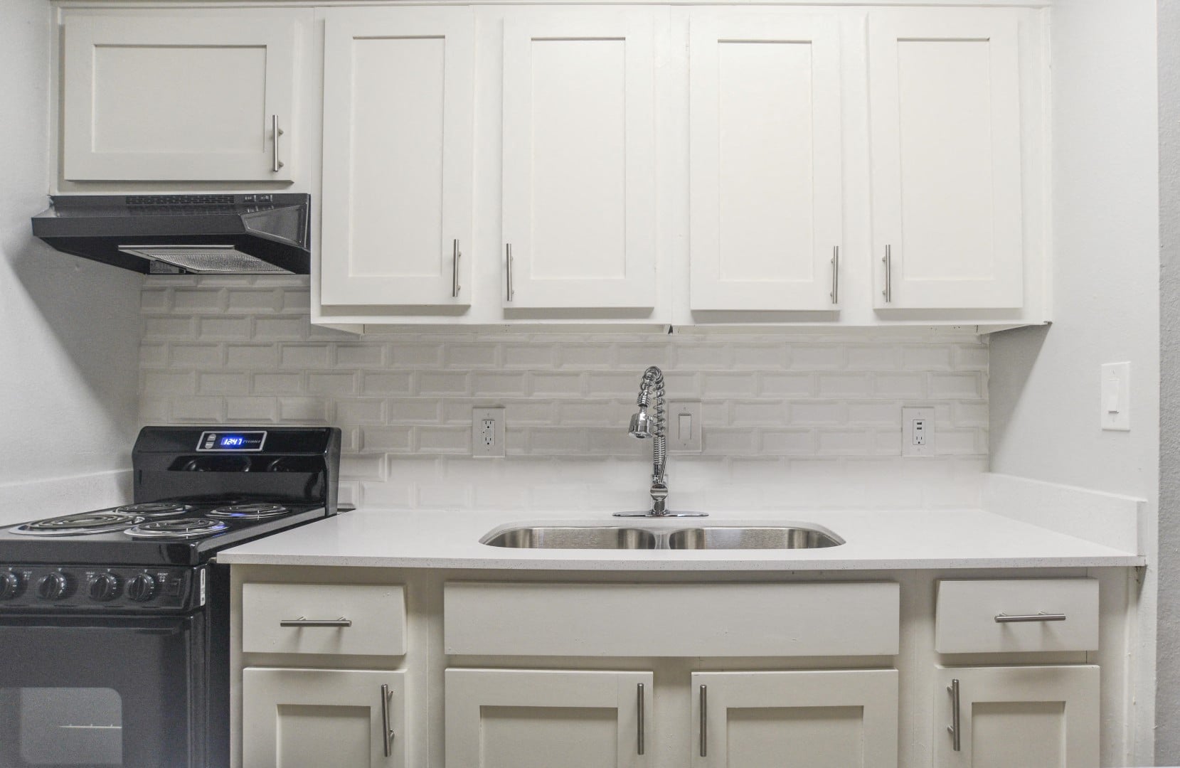 A kitchen with white cabinets and a black stove top.