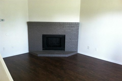 a living room with a stone fireplace and a wooden floor