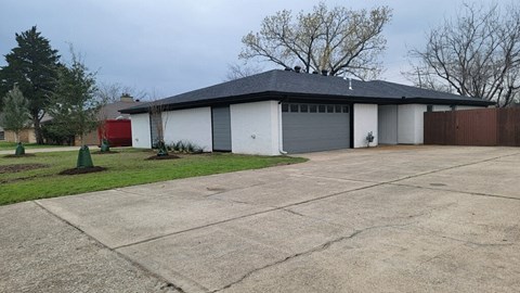 a white garage with a gray roof on top of a driveway