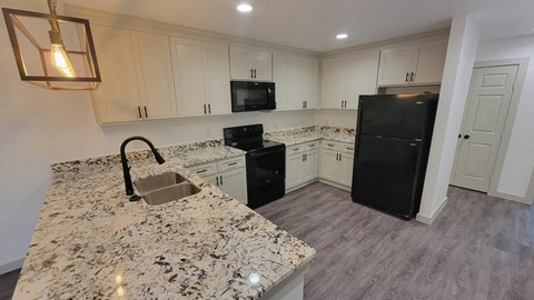 a kitchen with white cabinets and black appliances and granite counter tops