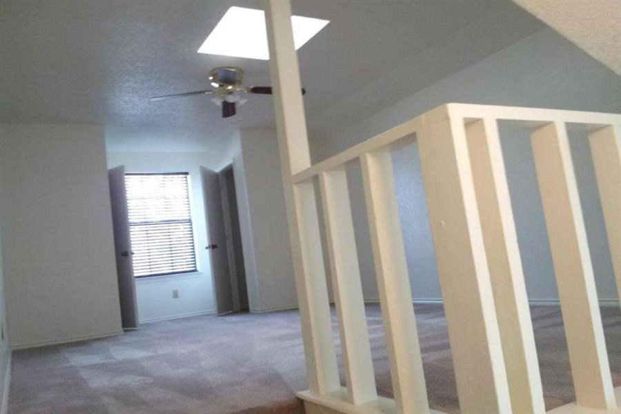 a living room with stairs and a ceiling fan