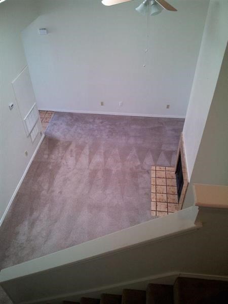 an empty room with a ceiling fan and a staircase