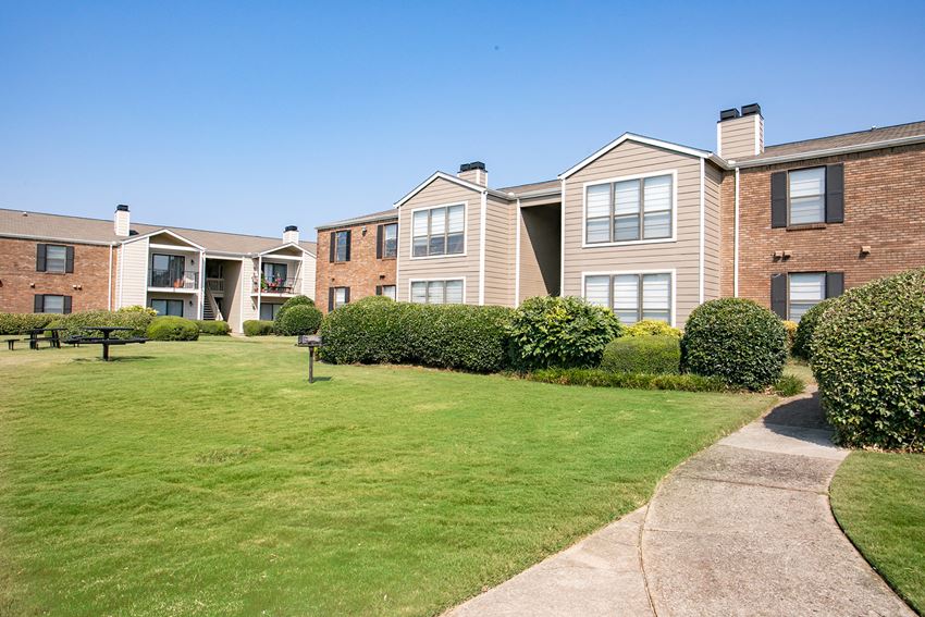 an apartment building with a green lawn and a sidewalk
