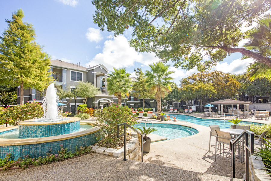 Swimming pool with water feature surrounded by lush landscape