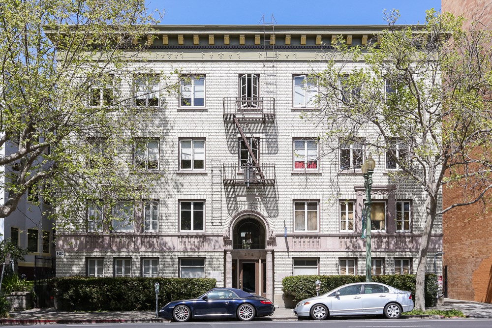 the apartment building has two cars parked in front of it