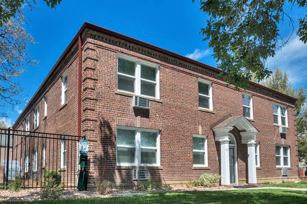 an old brick building with a fence in front of it
